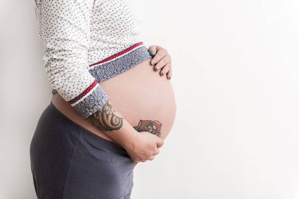 Pregnant woman putting hands on round paunch - Foto, afbeelding