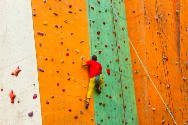 Активный юноша на скале в спорткомплексе
 - Фото, изображение