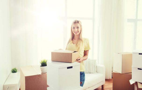 smiling young woman with cardboard box at home - Fotografie, Obrázek