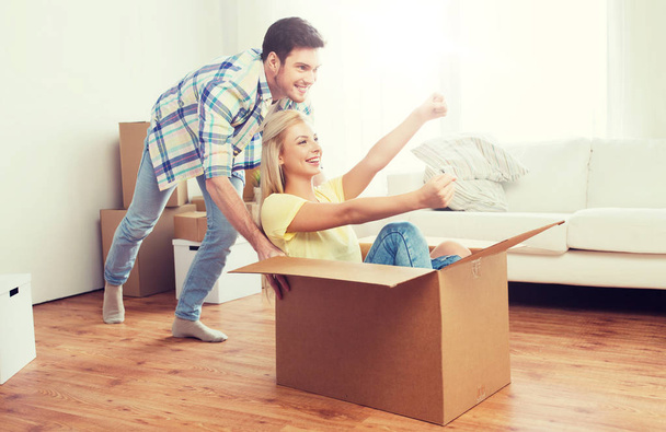 happy couple having fun with boxes at new home - Foto, imagen