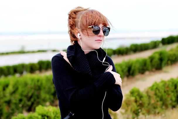 redhead woman  listening to music outdoor  - Фото, зображення