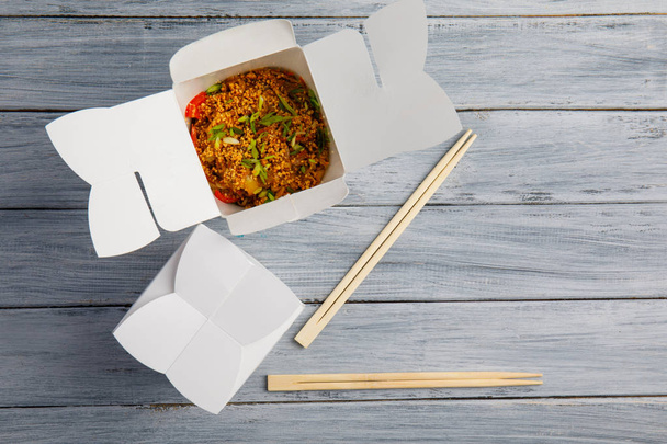 Noodles with vegetables in a box for export on a wooden table - 写真・画像