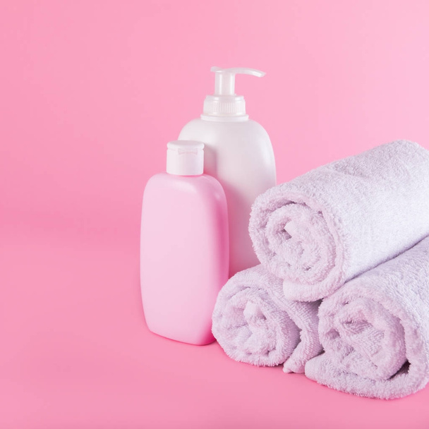 Towels with shower gel and body lotion on pink background. - Фото, зображення
