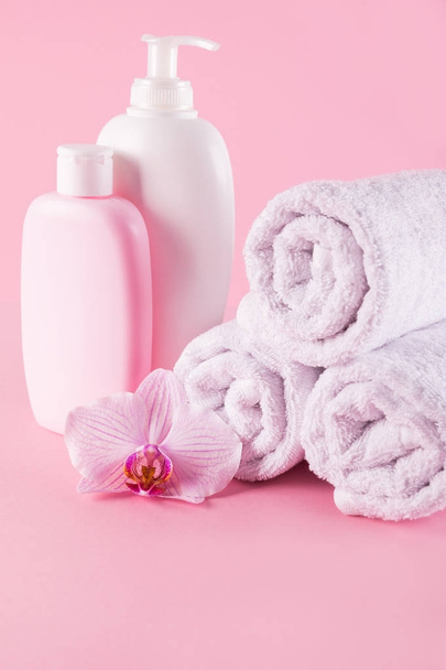 Towels with shower gel and body lotion on pink background. - Zdjęcie, obraz