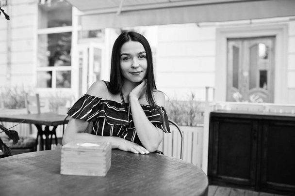 Gorgeous brunette girl sitting on the table in cafe. - Фото, зображення