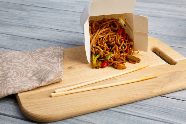 Chinese noodles in a box on a gray table. - Foto, Bild