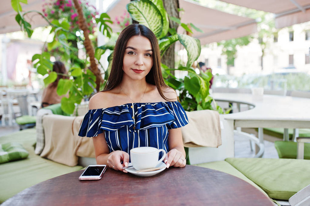 Gorgeous brunette girl sitting on the table in cafe with cup of  - Photo, Image
