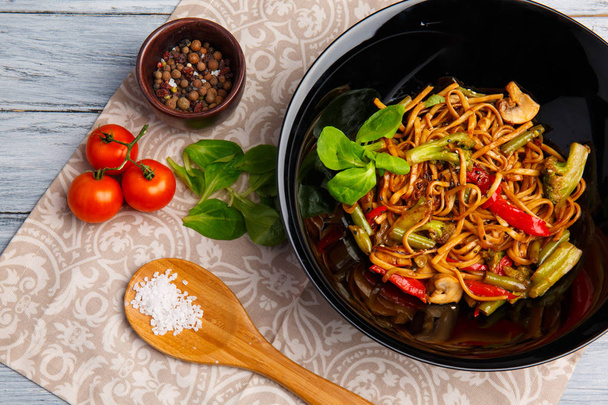 Prato chinês tradicional em uma chapa redonda, macarrão de arroz, repolho repolho verde e verduras fritas, tomates cereja vermelhos
. - Foto, Imagem