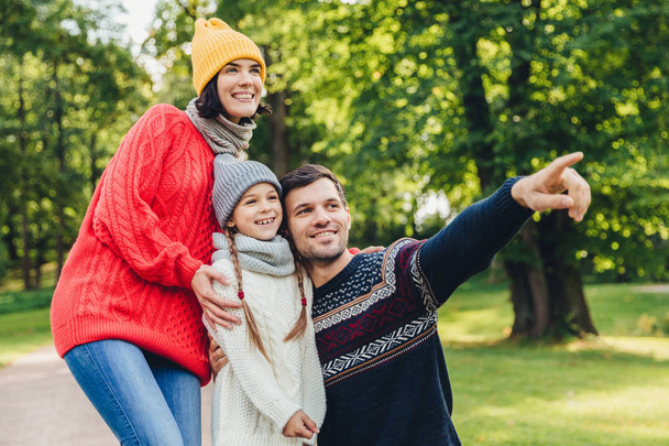 Három család tagjai időt együtt, nézni a tó, a park, azt mutatják, ujjaival, hogy a jó hangulat, kellemesen mosolyogva. Apa, anya és lánya élvezze összetartozás, nyugodt légkörben - Fotó, kép