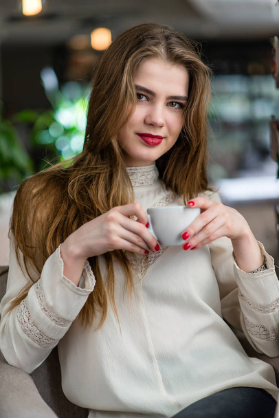 Beautiful young girl with professional makeup and hairstyle sitting in restaurant. - Zdjęcie, obraz