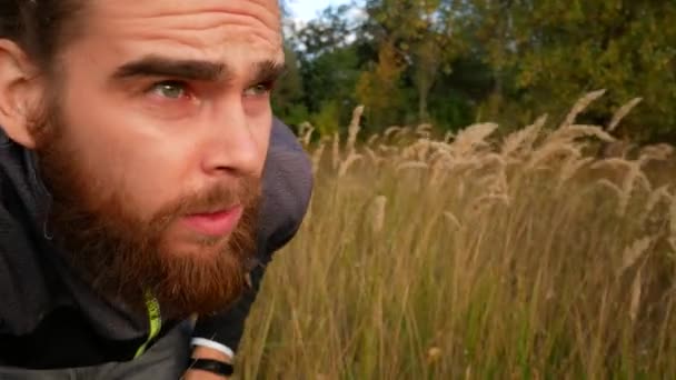 A man sneaks through the grass. A frightened guy looks ahead. - Imágenes, Vídeo