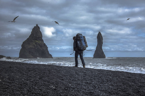 Tourist mit Rucksack am schwarzen Sandstrand, Vik in Island - Foto, Bild