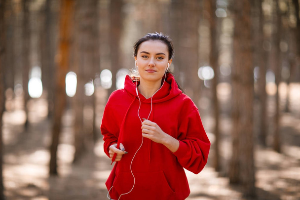 Young brunette athlete runs in the autumn forest. - Foto, imagen