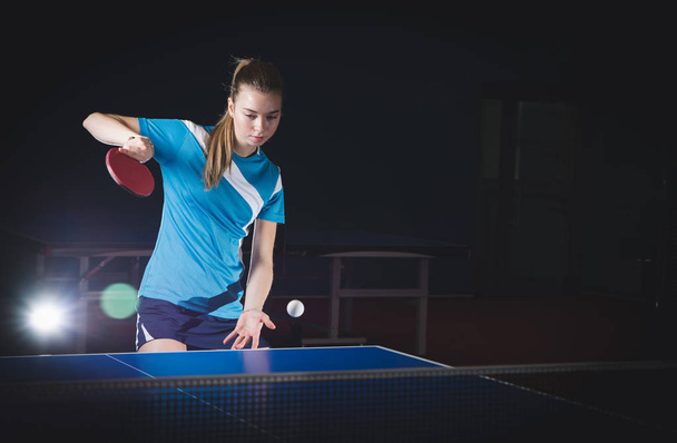 a girl plays table tennis, takes the ball - Foto, afbeelding