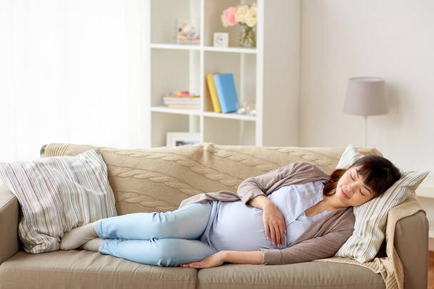 happy pregnant woman sleeping on sofa at home - Zdjęcie, obraz