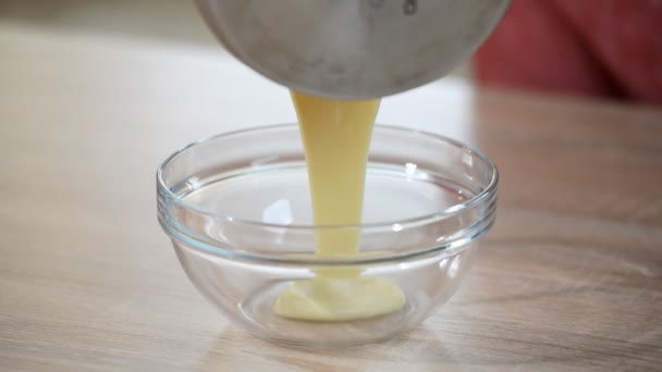 Hot creme being poured into mixing bowl to create a custard mix for a creme brulee dessert. - Séquence, vidéo