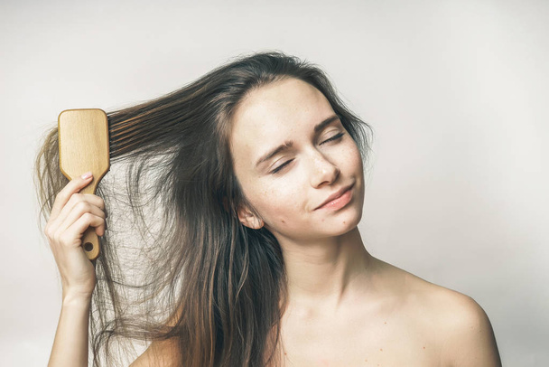 the girl tries to comb her long hair - Foto, afbeelding