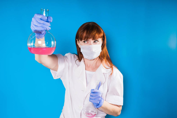 a woman in a face mask holds a flask of chemicals in her hands - Φωτογραφία, εικόνα