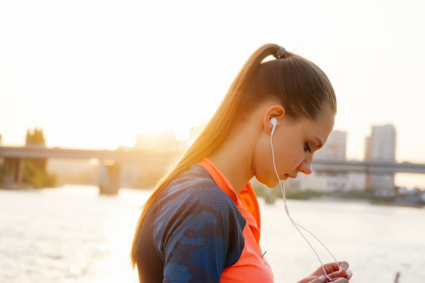 girl runs around the river in headphones with music - Foto, imagen