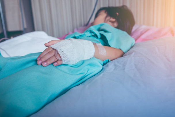 Maladie enfant asiatique admis à l'hôpital avec perfusion intraveineuse saline (IV) sous la main
. - Photo, image