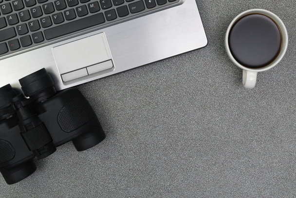 Laptop computer or notebook, binocular and cup of coffee on work - 写真・画像