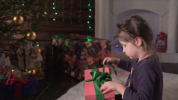 The girl opens her Christmas gift - Materiał filmowy, wideo