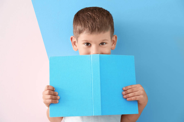 Cute little boy with book on color background - Photo, Image