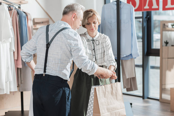 Frau schenkt Mann Einkaufstüten - Foto, Bild