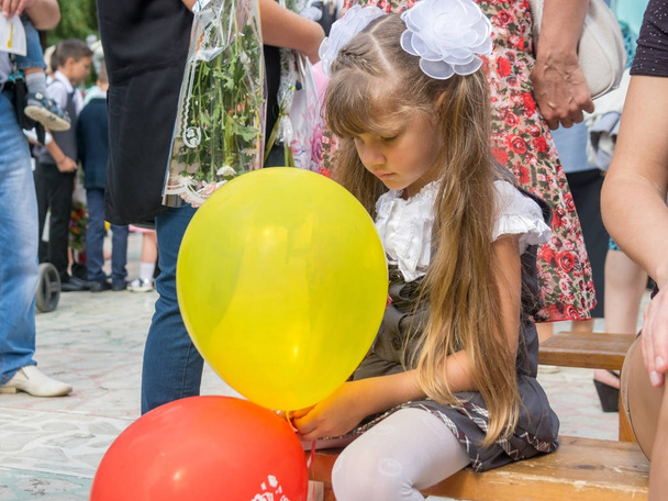 Chica triste sentado con bolas en las manos en septiembre 1 día festivo
 - Foto, imagen