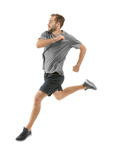 Young man in sportswear running on white background - Фото, изображение