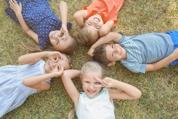 Group of children lying on green grass in park - Photo, Image