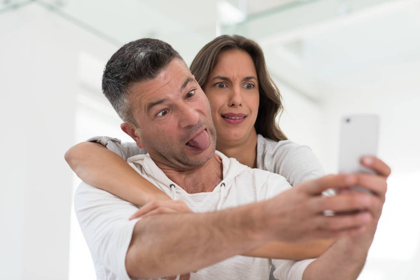 Ευτυχισμένο ζευγάρι που χρησιμοποιεί το κινητό τηλέφωνο στο σπίτι - Φωτογραφία, εικόνα