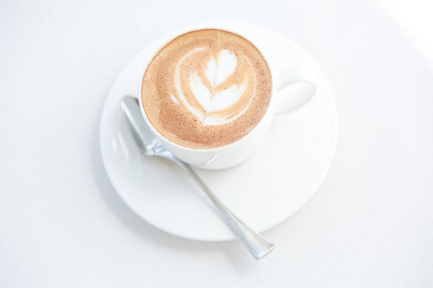 Kuppi cappuccinoa tai lattea pöydällä
 - Valokuva, kuva