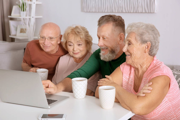 Groupe de personnes âgées avec ordinateur portable à la maison
 - Photo, image