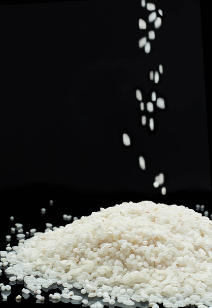 Raw white rice grain on black background - Foto, imagen