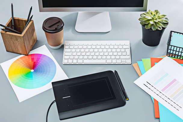 Серый стол с ноутбуком, блокнот с чистым листом, цветочный горшок, стилус и планшет для ретуши
 - Фото, изображение