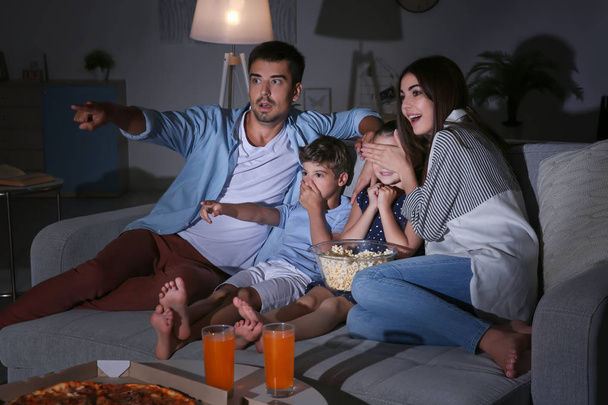 Happy family watching TV on sofa at night - 写真・画像