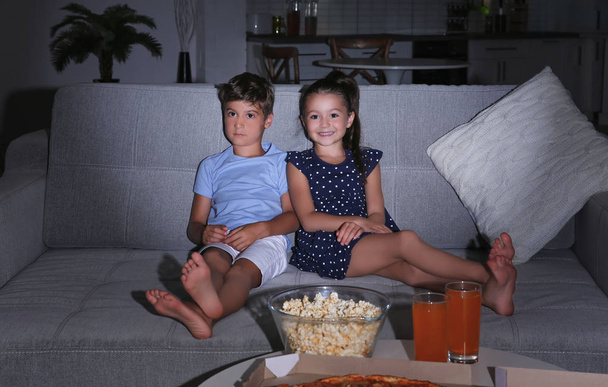 Cute children watching TV on sofa at night - Foto, Imagen