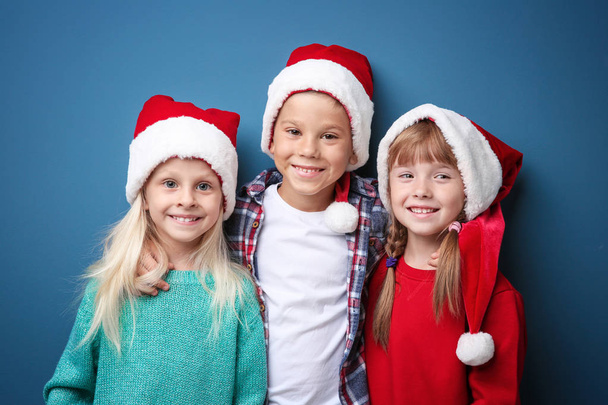 Cute children in Santa hats on color background. Christmas concept - Photo, image