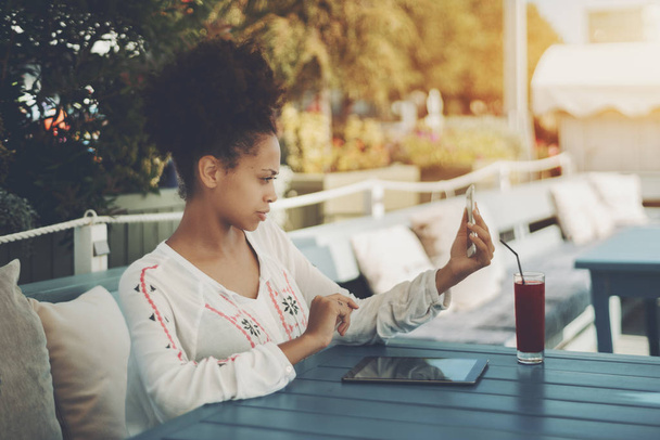 Menina birracial no bar de rua com smartphone e pad digital
 - Foto, Imagem