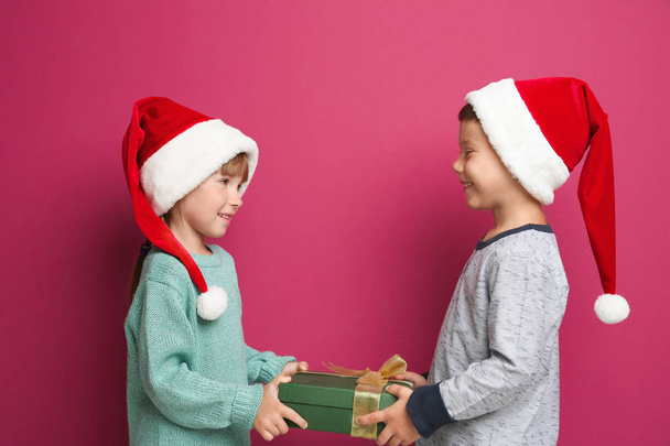 Cute little children with Christmas present on color background - Fotoğraf, Görsel