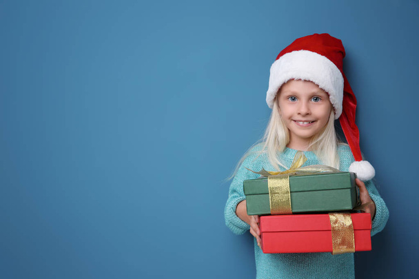 Cute little girl with Christmas present on color background - Foto, Imagem