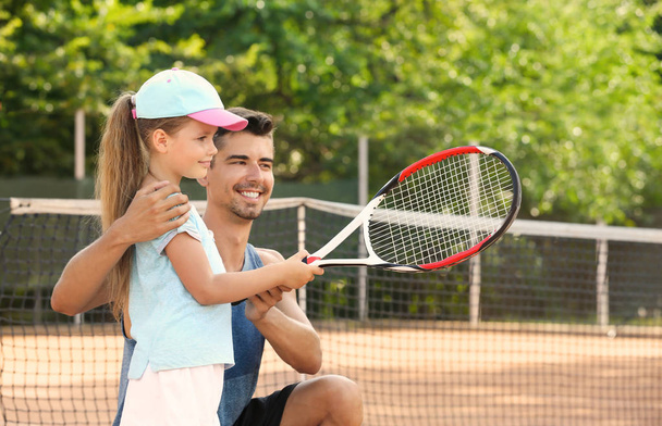 Young trainer with little girl on tennis court - Foto, afbeelding