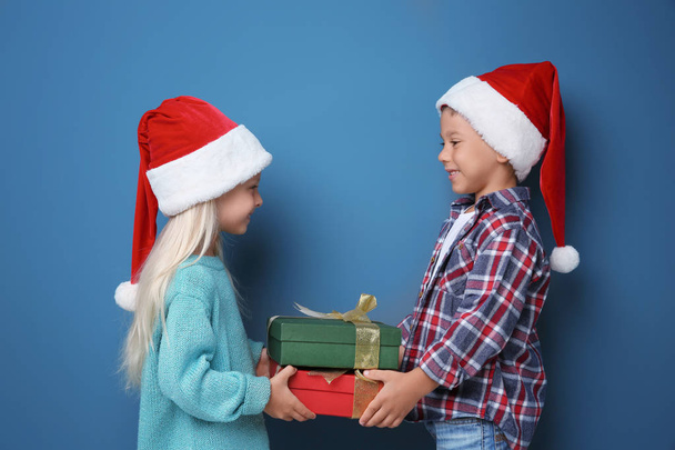 Cute little children with Christmas presents on color background - Foto, Bild