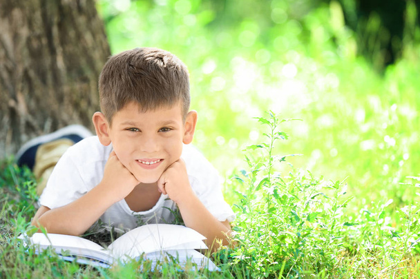Cute little boy reading book in park - Фото, зображення