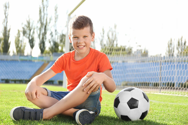 Roztomilý chlapec s fotbalovým míčem na hřišti - Fotografie, Obrázek