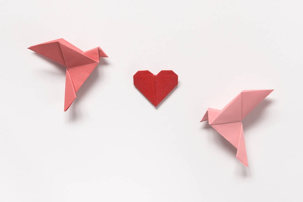 rosa Vögel und rotes Origamiherz auf weißem Hintergrund. Geschenk - Foto, Bild