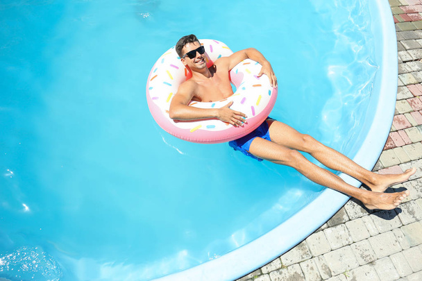 Young man with inflatable donut  - Fotoğraf, Görsel