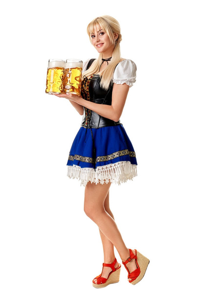 Full length portrait of a blond woman with traditional costume holding beer glasses isolated on white background. - Фото, изображение