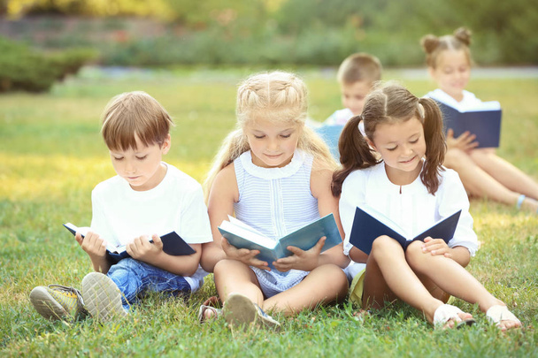 Χαριτωμένα παιδάκια διαβάζοντας βιβλία στο πάρκο - Φωτογραφία, εικόνα